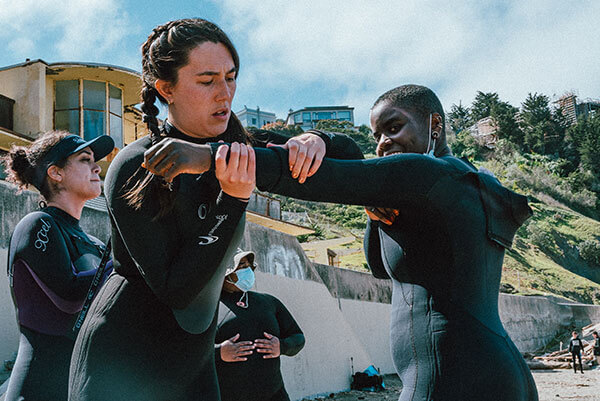 adult assisting another adult with wetsuit